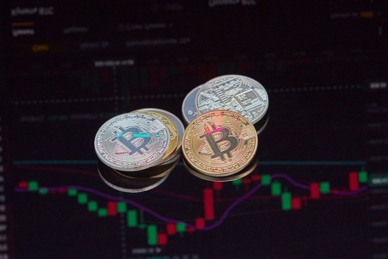 Moedas de Bitcoin sobre um gráfico do mercado financeiro, representando a negociação de ativos digitais.