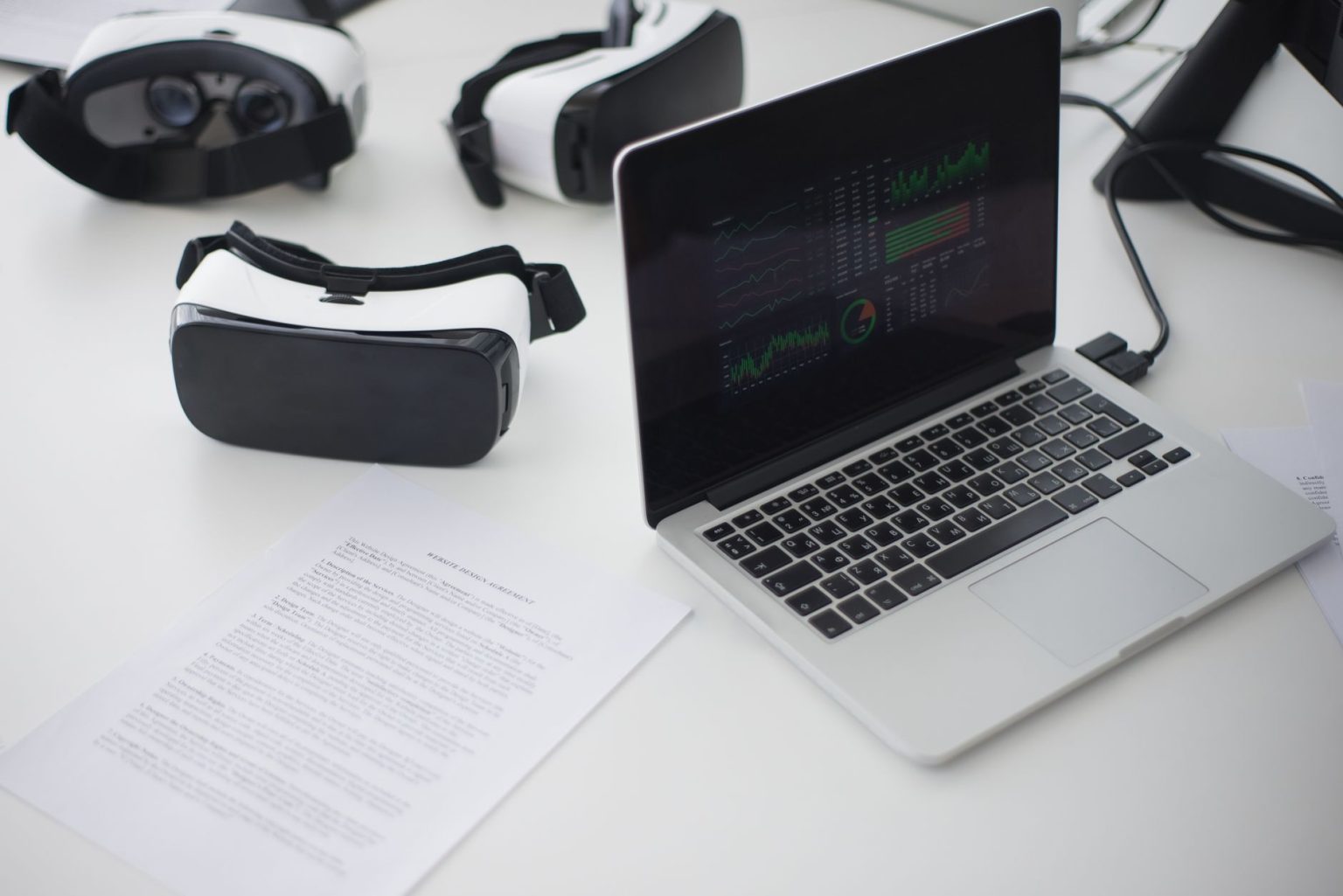 Ambiente de trabalho moderno com um laptop e dois headsets de realidade virtual sobre a mesa.